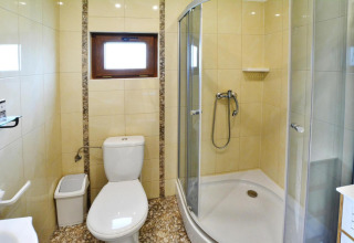 Bright bathroom at Domki letniskowe Rusinowo featuring shower cabin, toilet and window in Denmark.