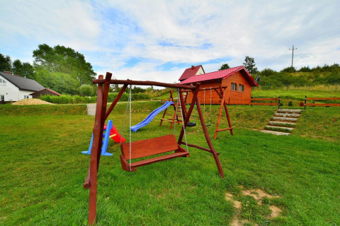 Playground with wooden swings and a slide near a cabin at Domki letniskowe Rusinowo in Denmark.