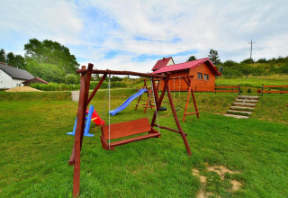 Playground with wooden swings and a slide near a cabin at Domki letniskowe Rusinowo in Denmark.
