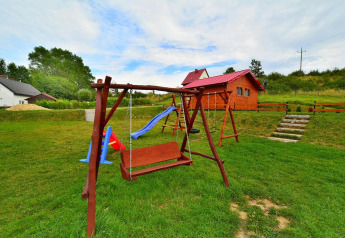 Speeltuin met houten schommel en glijbaan bij chalet Domki letniskowe Rusinowo in Denemarken.