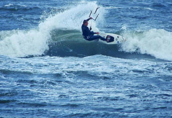 Kitesurfista montando una ola cerca de Domki letniskowe Rusinowo, escena emocionante en Dinamarca.