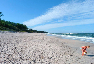 Photo of a quiet sandy beach near Domki letniskowe Rusinowo, with a girl playing with a ball by the sea.