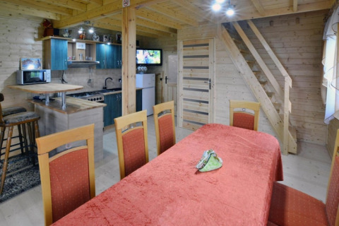 Innenaufnahme von Domek letniskowy PATRYK Ostrowiec Slawienski Lodge mit Essbereich, Küche und Holztreppe.