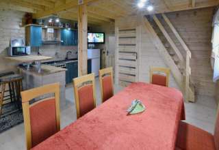 Innenaufnahme von Domek letniskowy PATRYK Ostrowiec Slawienski Lodge mit Essbereich, Küche und Holztreppe.