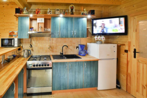 Gemütliche Holzhütte-Küche mit blauen Schränken, Herd, Kühlschrank und Wandfernseher.