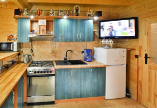 Gemütliche Holzhütte-Küche mit blauen Schränken, Herd, Kühlschrank und Wandfernseher.