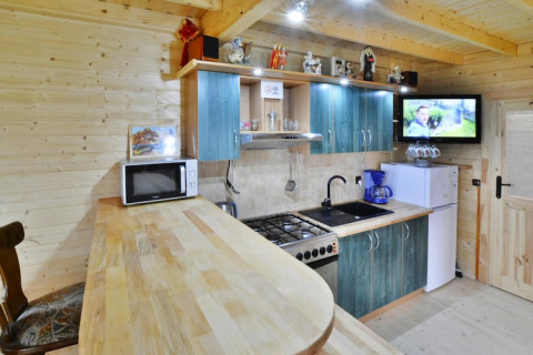 Moderne Küchenzeile in einer Holzhütte mit blauen Schränken, Herd, Mikrowelle, Kühlschrank und Fernseher.
