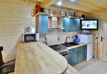 Moderne keuken in een houten lodge met blauwe kasten, fornuis, microgolf, koelkast en wand-tv.