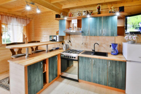 Gemütliche Holzküche mit grünen Schränken, Essbereich, Herd und Kühlschrank in Domek letniskowy PATRYK.