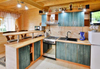 Gemütliche Holzküche mit grünen Schränken, Essbereich, Herd und Kühlschrank in Domek letniskowy PATRYK.
