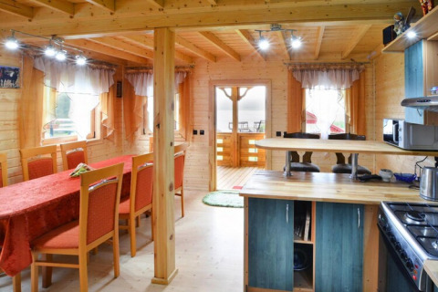 Innenansicht der Lodge Domek letniskowy PATRYK Ostrowiec Slawienski mit Essbereich, Küche und Holzinterieur.