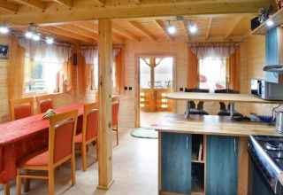 Innenansicht der Lodge Domek letniskowy PATRYK Ostrowiec Slawienski mit Essbereich, Küche und Holzinterieur.