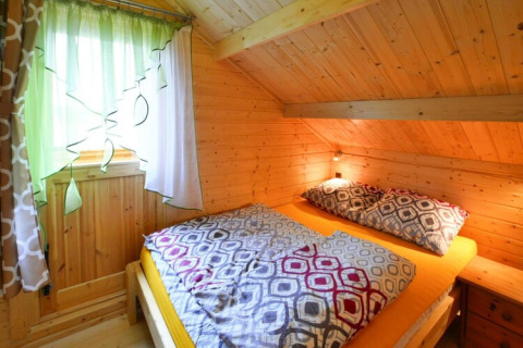 Ein gemütliches Schlafzimmer mit Holzwänden, bunten Vorhängen und Doppelbett in Domek letniskowy PATRYK.