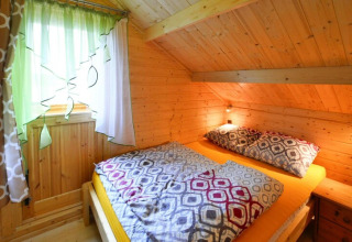 Ein gemütliches Schlafzimmer mit Holzwänden, bunten Vorhängen und Doppelbett in Domek letniskowy PATRYK.