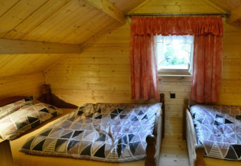 Camera con due letti singoli, pareti e soffitto in legno e piccola finestra nel lodge Domek letniskowy PATRYK.