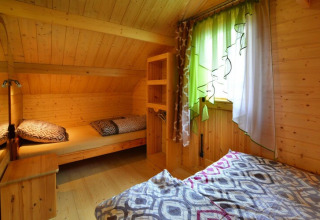 Gemütliches Holzschlafzimmer mit zwei Betten und bunten Vorhängen in Domek letniskowy PATRYK Ostrowiec Slawienski, Dänemark.