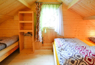 Gemütliches Schlafzimmer mit zwei Einzelbetten, Holzwänden und Fenster im Domek letniskowy PATRYK.