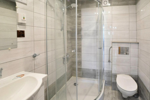 Modernes Bad mit Glasdusche, wandhängender Toilette und weißen Fliesen in Domek letniskowy PATRYK.