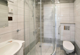 Modernes Bad mit Glasdusche, wandhängender Toilette und weißen Fliesen in Domek letniskowy PATRYK.