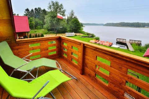 Blick von einem Balkon mit grünen Liegestühlen auf einen See und Boote, Domek letniskowy PATRYK Ostrowiec Slawienski.