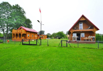 Photo of Domek letniskowy PATRYK Ostrowiec Slawienski, a cozy lodge with a grassy yard and wooden buildings.