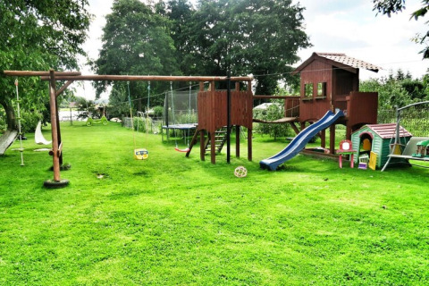 Spielplatz im Freien beim Domek letniskowy PATRYK Ostrowiec Slawienski mit Rutsche, Schaukeln und Grünfläche.