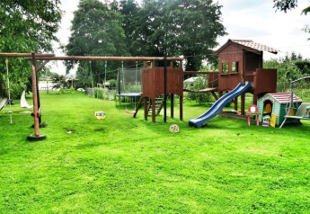 Outdoor playground at Domek letniskowy PATRYK Ostrowiec Slawienski with swing set, slide, grass, and playhouse.