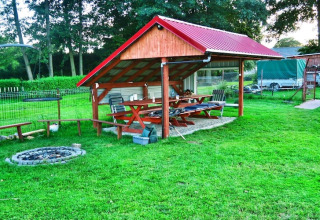 Überdachter Sitzbereich im Freien mit Bänken und Feuerstelle bei Domek letniskowy PATRYK Ostrowiec Slawienski, Dänemark.