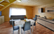 Vista interna di uno chalet in legno con tavolo da pranzo, quattro sedie, divano e angolo cottura a Jarosławiec.
