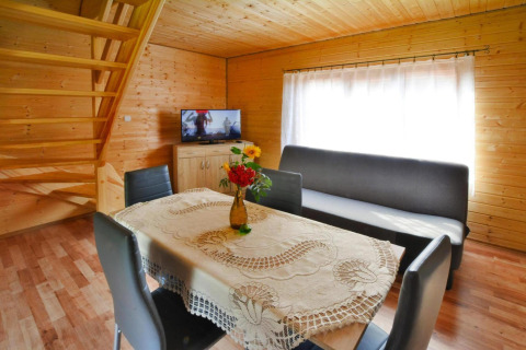 Woonruimte in Domek 5-osobowy Jarosławiec, Denemarken met eettafel, bank, tv en houten interieur.