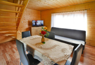 Woonruimte in Domek 5-osobowy Jarosławiec, Denemarken met eettafel, bank, tv en houten interieur.