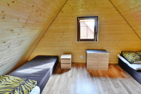 Houten kamer met twee eenpersoonsbedden, tijgerkussens en raam in Domek 5-osobowy Jarosławiec lodge.