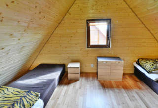 Houten kamer met twee eenpersoonsbedden, tijgerkussens en raam in Domek 5-osobowy Jarosławiec lodge.