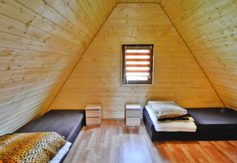 Holzverkleidetes Zimmer im Domek 5-osobowy Jarosławiec mit zwei Betten, Fenster und Nachttischen.
