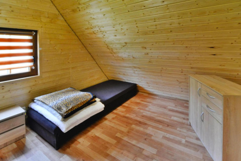 Eenvoudige houten slaapkamer met eenpersoonsbed, ladekast en raam in Domek 5-osobowy Jarosławiec, Denemarken.