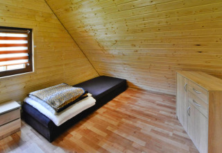 Eenvoudige houten slaapkamer met eenpersoonsbed, ladekast en raam in Domek 5-osobowy Jarosławiec, Denemarken.