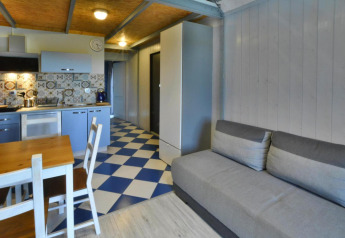 Modern lodge at Jezierzany with gray sofa, open kitchen, tiled backsplash and checkered floor.
