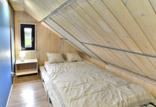 Soveværelse i Domki wakacyjne Jezierzany-lodgen med skrå loft, dobbeltseng og natbord.