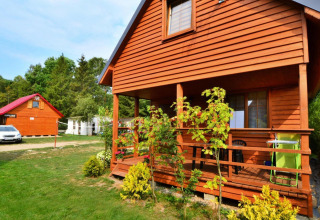Houten lodge Domek 5-osobowy Jarosławiec met veranda, tuinplanten en auto in Denemarken.