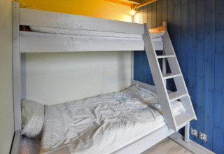 Værelse med køjeseng og blå trævæg på lodge 'Domki wakacyjne Jezierzany' i Danmark, moderne design.