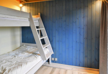 Lichte kamer met stapelbedden en een blauwe houten wand bij Domki wakacyjne Jezierzany in Denemarken.