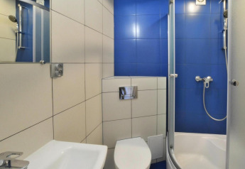 Modern bathroom with blue and white tiles, shower cabin, toilet and sink at Domki wakacyjne Jezierzany lodge.