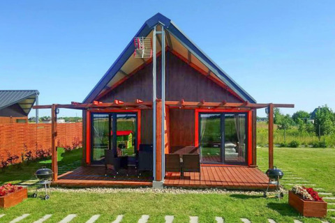 Et moderne sommerhus ved «Domki wakacyjne Jezierzany» i Danmark, med træterrasse og grøn have.