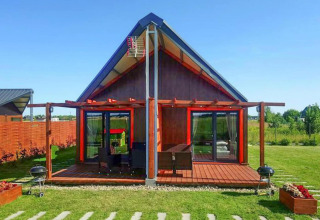 Et moderne sommerhus ved «Domki wakacyjne Jezierzany» i Danmark, med træterrasse og grøn have.