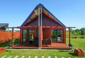 Cabaña moderna en «Domki wakacyjne Jezierzany» en Dinamarca, con terraza de madera y césped verde.