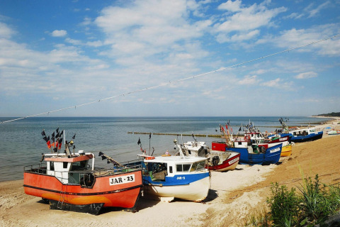 Vissersboten op het strand bij zee onder een blauwe lucht in Jarosławiec, Denemarken, zomers sfeerbeeld.