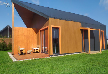 Lodge moderne en bois avec une grande terrasse et pelouse verdoyante à Domki wakacyjne Jezierzany au Danemark.