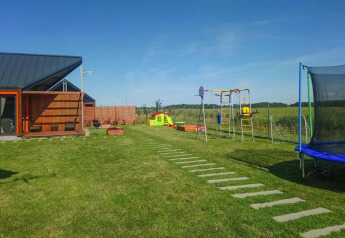 Parque infantil y lodge moderno en Domki wakacyjne Jezierzany, Dinamarca, con césped y zona de juegos.
