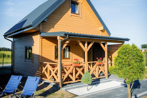 Houten lodge bij Ustecka Osada 45m2 met veranda, bloemenbakken en blauwe ligstoelen buiten.