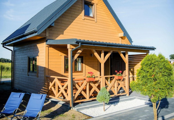 Houten lodge bij Ustecka Osada 45m2 met veranda, bloemenbakken en blauwe ligstoelen buiten.